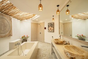 Ein modernes Badezimmer mit einer großen Badewanne, einem Holzwaschtisch und einem großen Spiegel.
