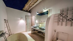 Ein Badezimmer mit einer Badewanne, einem Waschbecken mit Spiegel, einer Toilette und einem Ablagebereich für Toilettenartikel.