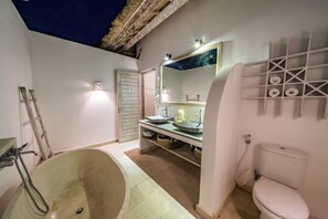Ein Badezimmer mit einer Badewanne, einem Waschbecken mit Spiegel, einer Toilette und einem Ablagebereich für Toilettenartikel.