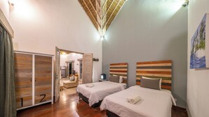 Ein Hotelzimmer mit zwei Betten, Holzboden, einer Deckenleuchte und einem Bild an der Wand.
