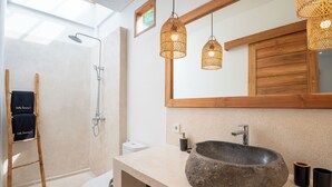 Un baño moderno con una bañera independiente, un espejo grande y un mueble de tocador de madera.