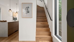 A modern kitchen with wooden cabinets, a white countertop, and pendant lighting. - Loft & Leaf Terrace Stanmore (Stanmore)