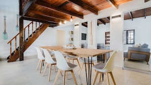 A dining area with a wooden table, white chairs, and a staircase with wooden railings. - 2 min Walk to Beach - Mangel Halto (Savaneta)