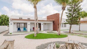 A modern house with a patio, two palm trees, and a well-maintained lawn. - 2 min Walk to Beach - Mangel Halto (Savaneta)
