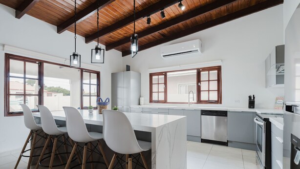 A modern kitchen with a large island, bar stools, and a view through the windows. - 2 min Walk to Beach - Mangel Halto (Savaneta)