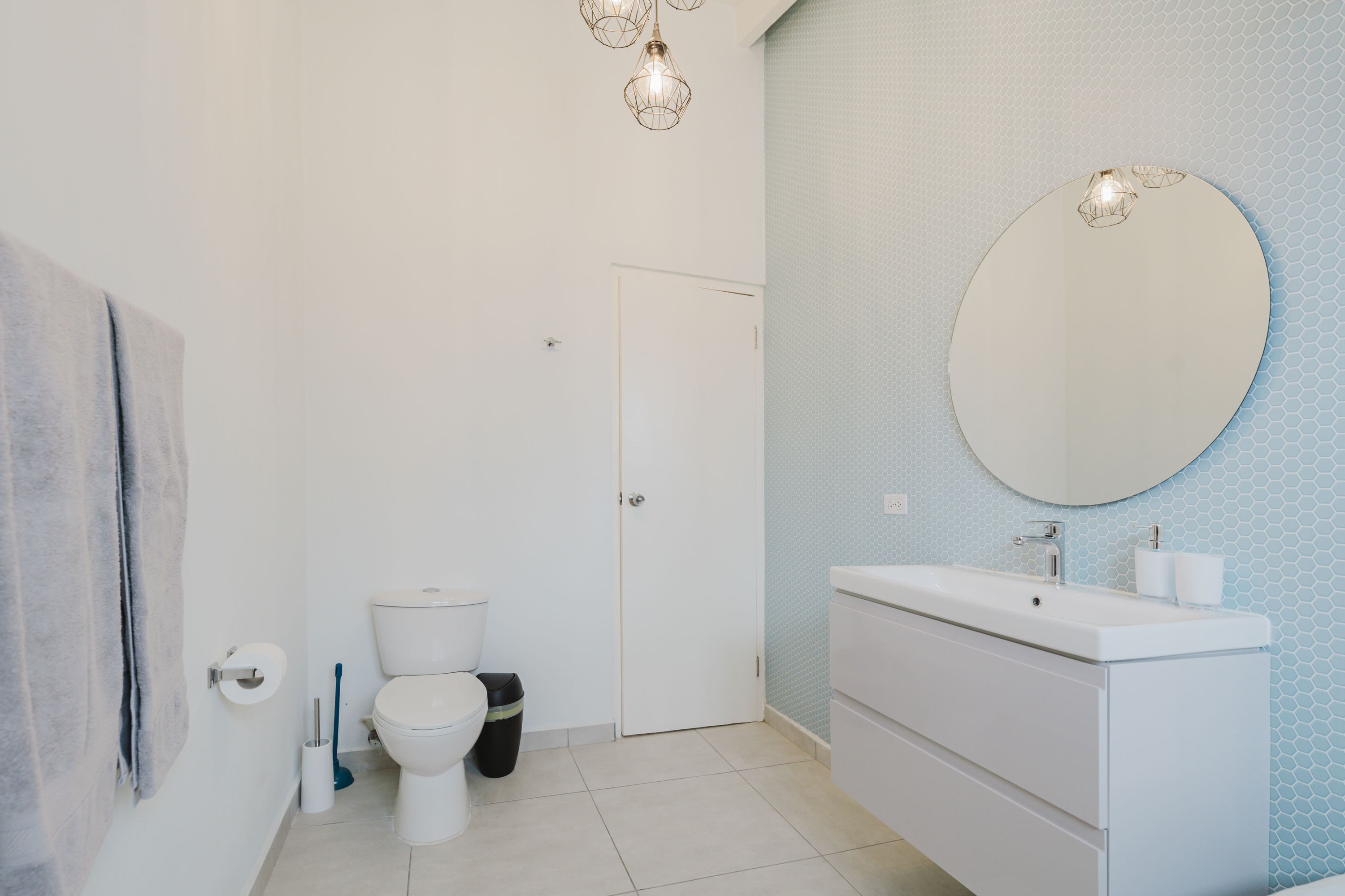 Een badkamer met toilet, wastafel, spiegel en handdoekhouder.