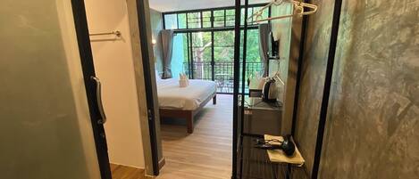 Une chambre d’hôtel moderne, dotée d’un lit, d’un balcon avec vue et d’un portant métallique pour les vêtements.