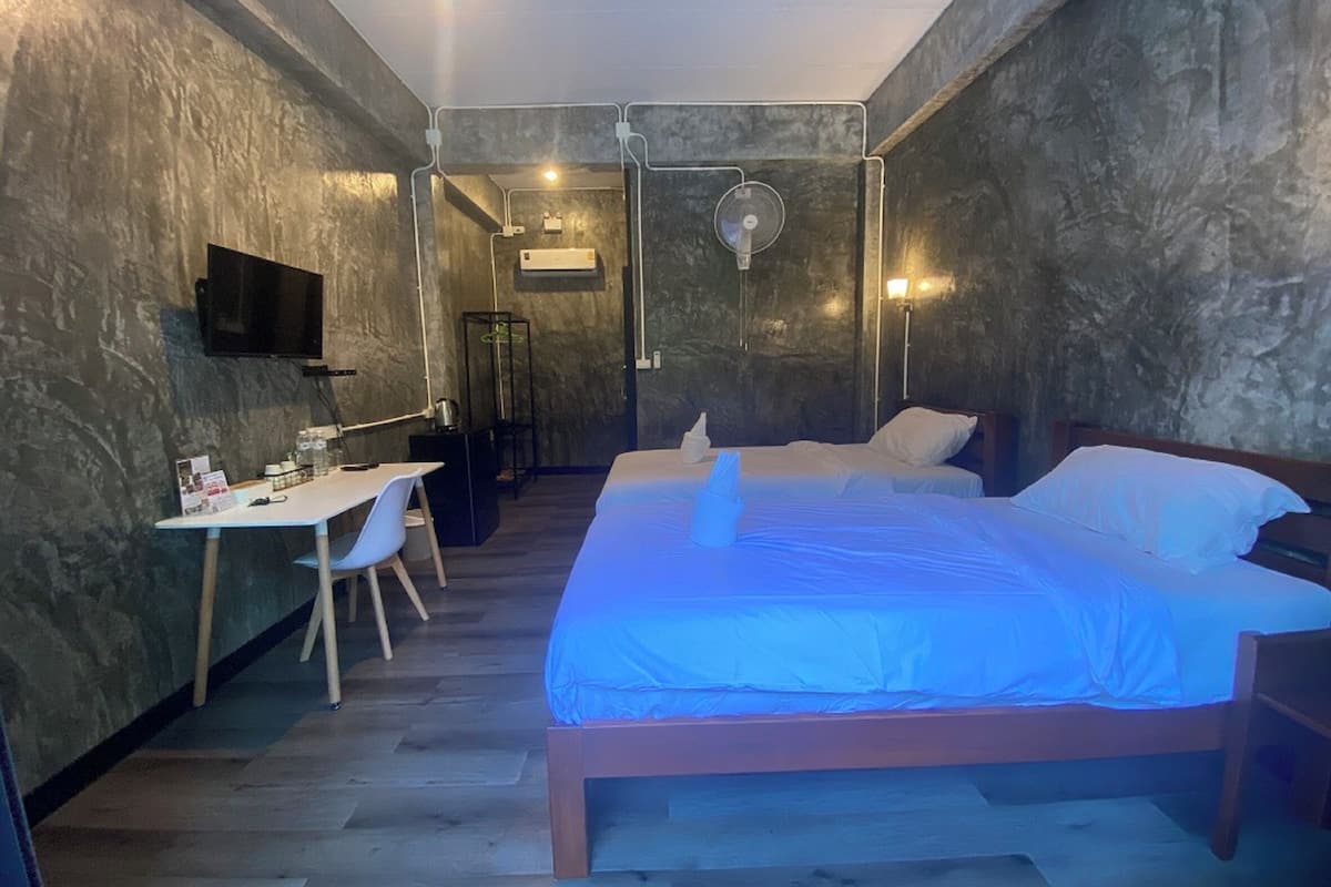 A room with a bed, a desk, a chair, a TV, and a fan.