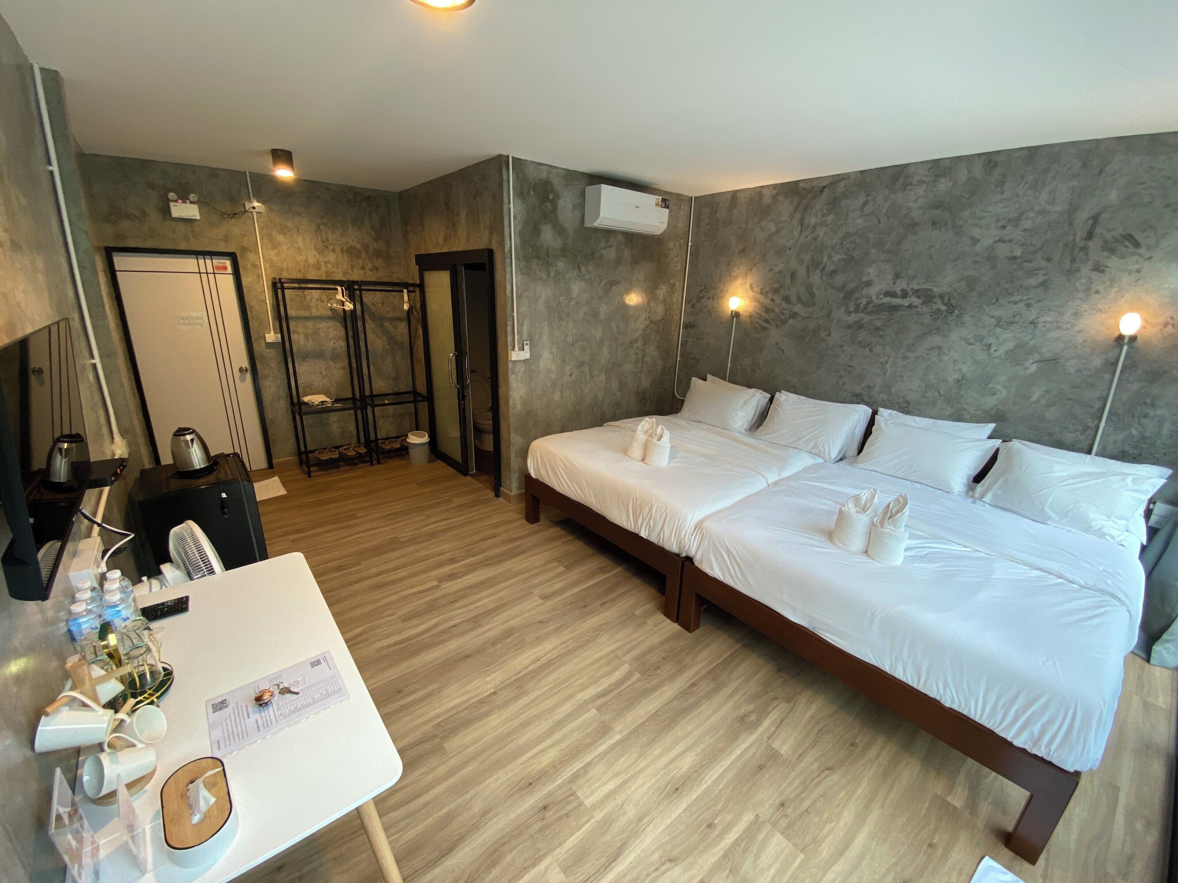 A hotel room with a large bed, a desk with toiletries, a mirror, and a wardrobe.