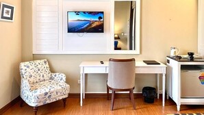 A room with a desk, a chair, a television mounted on the wall, a small table with a lamp, and a refrigerator. - The Boone resort (Doi Saket)