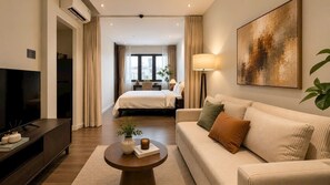 A modern hotel room with a bed, a sofa, a TV, and a painting on the wall. - Amana Living Nguyen Canh Chan (Cau Ong Lanh)