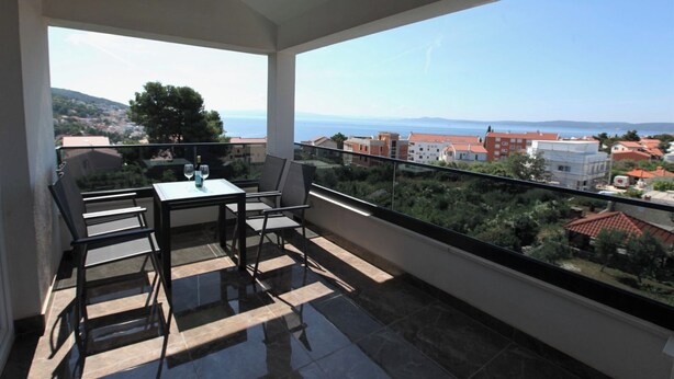 A balcony with a table and chairs, a clear view of the sea and buildings. -  Luxury Seaside Villa PIA Ground Floor (Okrug Gornji)