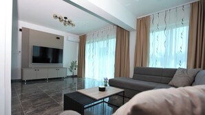 A modern living room with a sofa, a coffee table, and a TV on a cabinet. -  Luxury Seaside Villa PIA Ground Floor (Okrug Gornji)