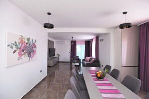 Una sala de estar moderna con comedor, televisor y una planta.