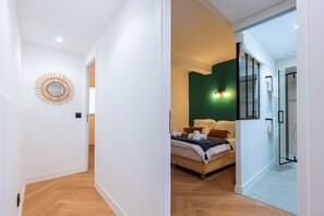 A modern bedroom with a bed, a mirror, and a green accent wall. - Superbe 3 pièces Carré d'Or, Parking & Clim (Nice)