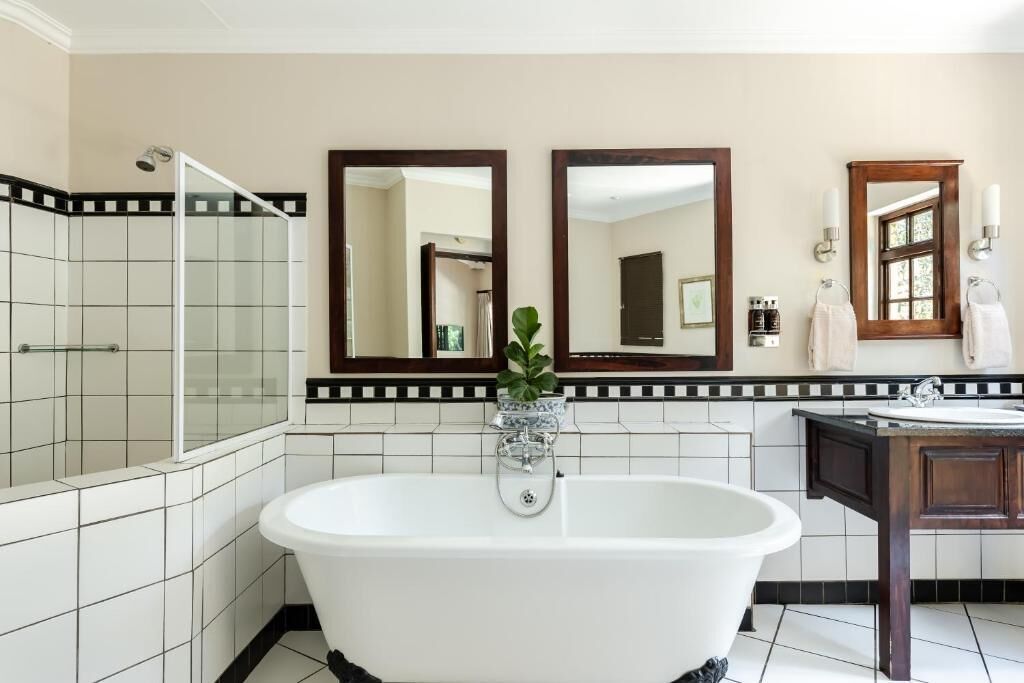 A bathroom with a freestanding bathtub, a glass-enclosed shower, and two wall-mounted mirrors.