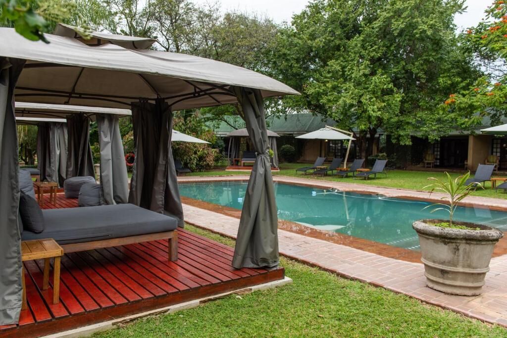 Zona de piscina con área de descanso cubierta, piscina y sillas de salón.