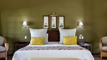 A hotel room with a large bed, two bedside tables, two wall-mounted lamps, and a headboard with three framed pictures.