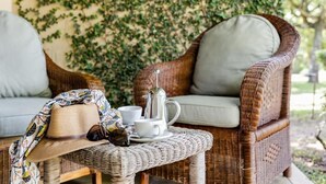 Wicker furniture with cushions, a table with a hat, sunglasses, and a coffee pot. - Perry's Bridge Hollow Boutique Hotel (Mbombela)