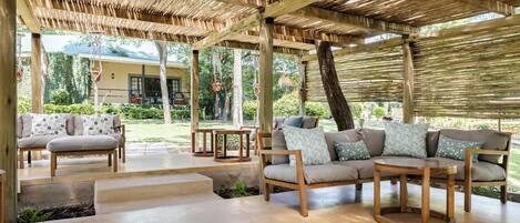 An outdoor seating area with wooden furniture and a thatched roof.