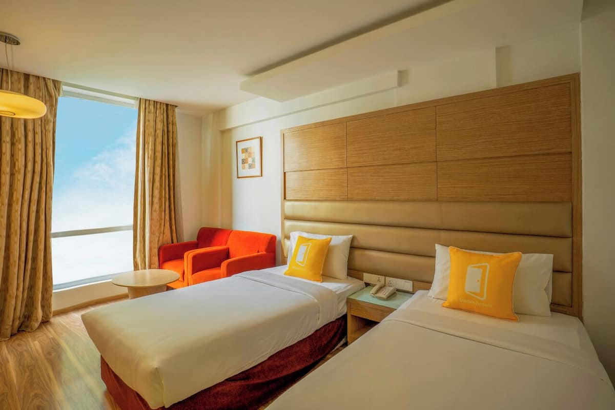Habitación de hotel con dos camas, un sofá, una mesita de noche, un teléfono y una ventana con cortinas.