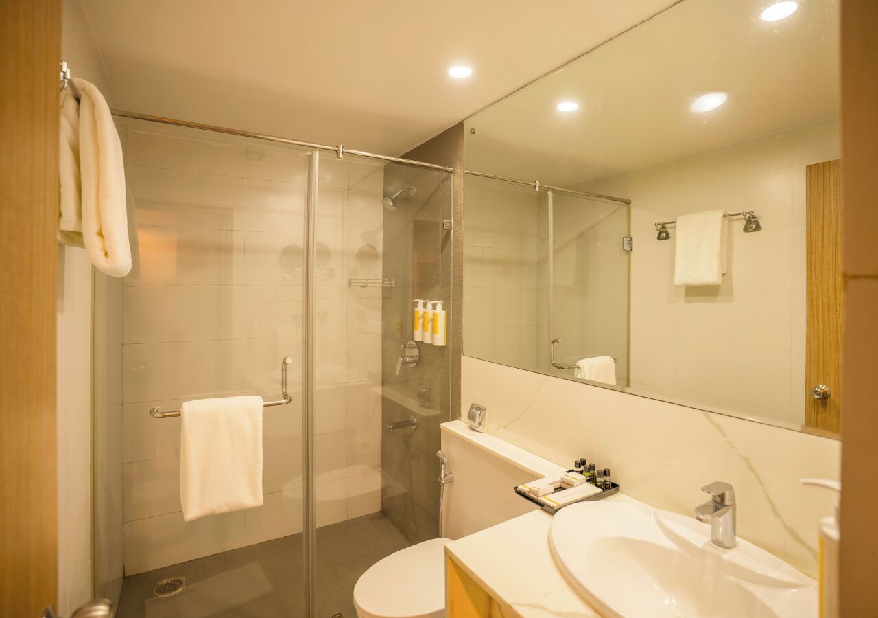 A modern bathroom with a glass shower enclosure, a toilet, a sink with a mirror, and a towel rack.