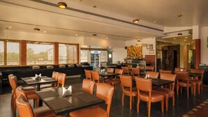 Um restaurante amplo com mesas e cadeiras altas, área de bar e um espaço de estar com bancos estofados.