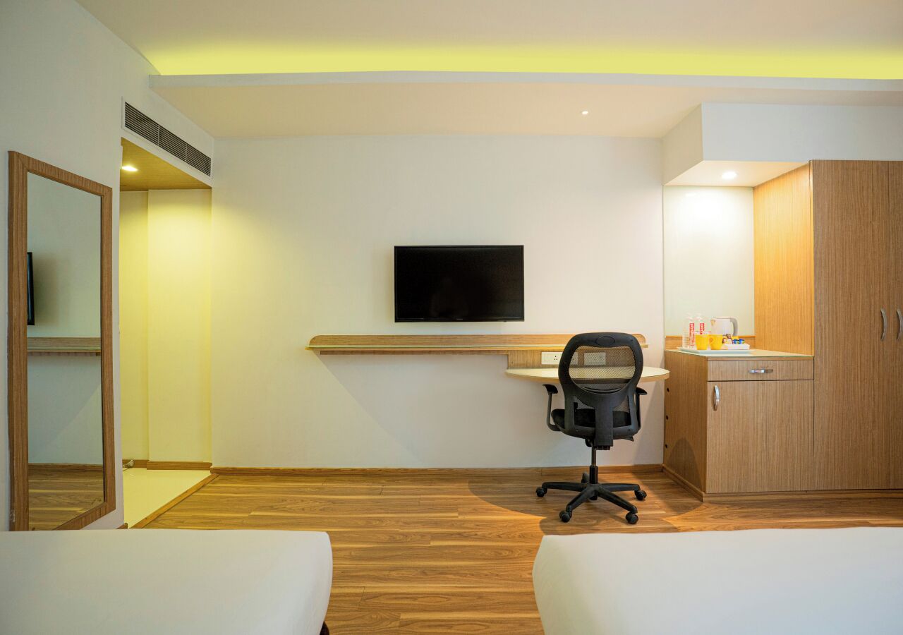 Une chambre d’hôtel équipée d’un lit, d’un bureau, d’une chaise, d’une télévision et d’une armoire en bois.