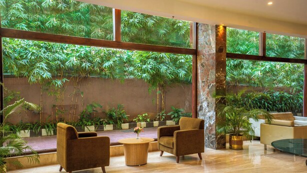 Um quarto amplo com grandes janelas, um sofá, poltronas e uma mesa de centro.