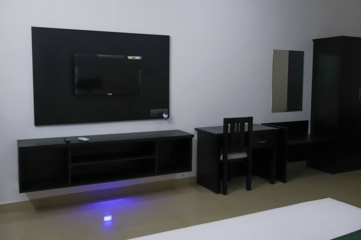 Una sala de estar moderna con un televisor de pantalla plana montado en la pared, un mueble bajo para equipo multimedia negro y un sofá negro con un sillón a juego.