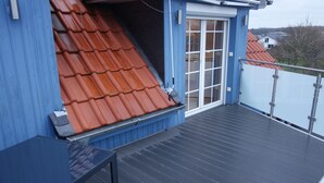 En blå byggnad med ett rött tak, en glasdörr och en balkong.