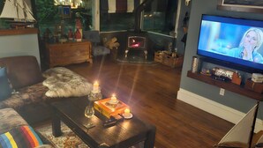 Ett mysigt vardagsrum med en öppen spis, en tv och en bekväm sittgrupp.