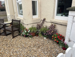 A patio with a wooden bench, potted plants, and a gravel ground.