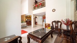 A spacious living area with a glass-top coffee table, wooden chairs, a red decorative item, and a traditional Chinese-style chair. - Collection O Dinh Dinh 2 - Near T3 (Ho Chi Minh City)