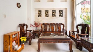 A traditional wooden sofa set with a glass-top coffee table, a wooden cabinet with decorative items, and a wall-mounted clock. - Collection O Dinh Dinh 2 - Near T3 (Ho Chi Minh City)