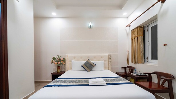 A neatly arranged hotel room with a large bed, bedside tables, a desk, and a chair. - Collection O Dinh Dinh 2 - Near T3 (Ho Chi Minh City)