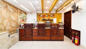 A reception desk with a wooden design, a clock, and a TV mounted on the wall. - Collection O Dinh Dinh 2 - Near T3 (Ho Chi Minh City)