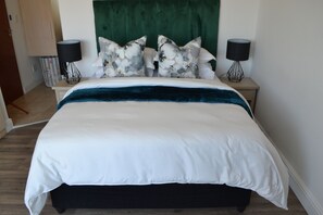 A bed with white bedding and a dark blue accent, flanked by two black lamps with wire frames. - Accessible City Retreat with Stunning Views and Pool Access (City of Cape Town Metropolitan Municipality)