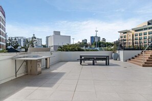 Eine Dachterrasse mit Tisch und Bank, umgeben von Gebäuden.