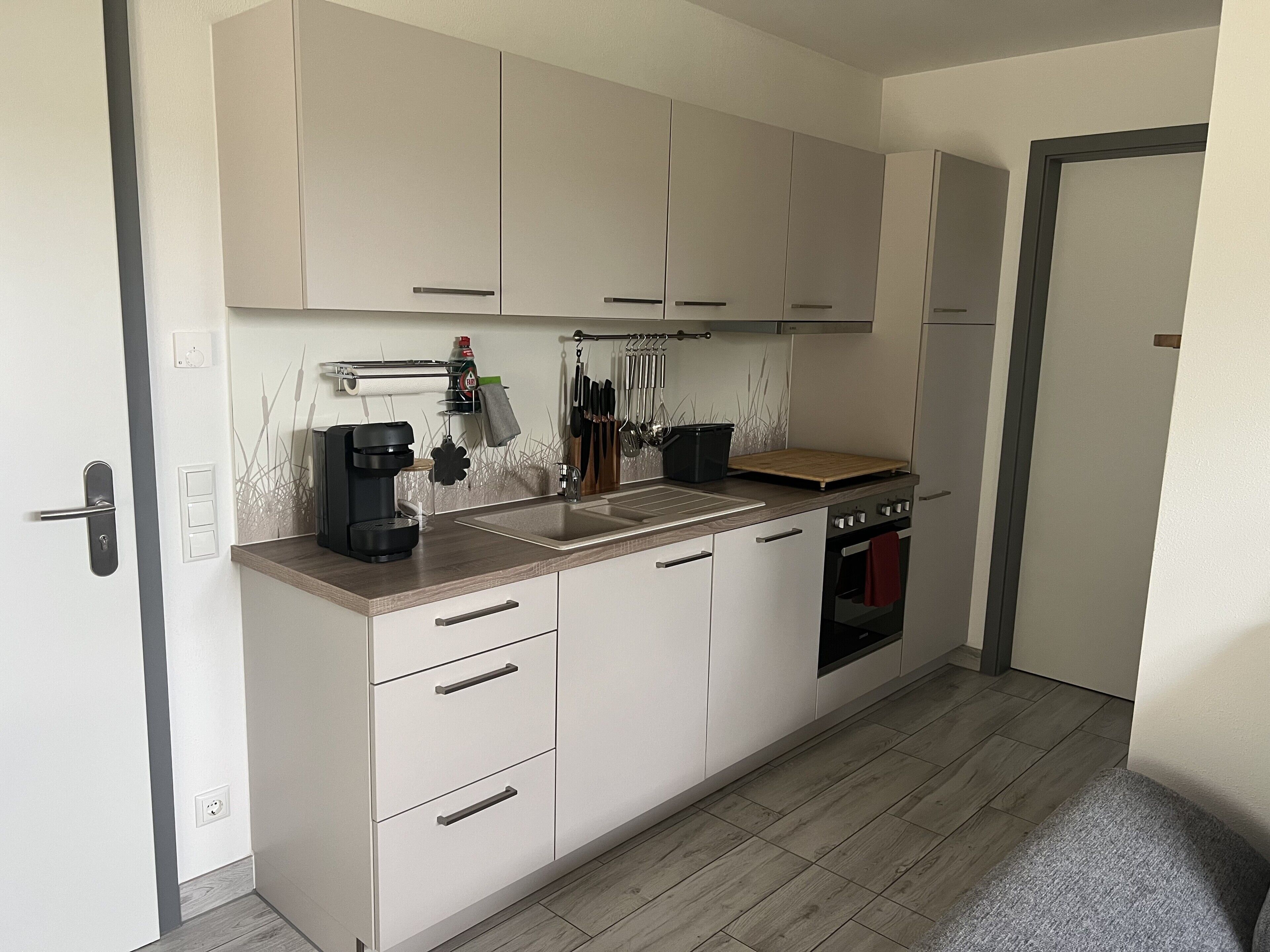 A compact kitchen with a built-in oven, a coffee maker, and a knife rack.