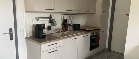 A compact kitchen with a built-in oven, a coffee maker, and a knife rack.
