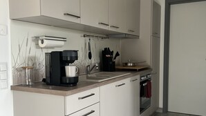 Een moderne keuken met witte kastjes, een houten aanrecht, een koffiezetapparaat en een fornuis.