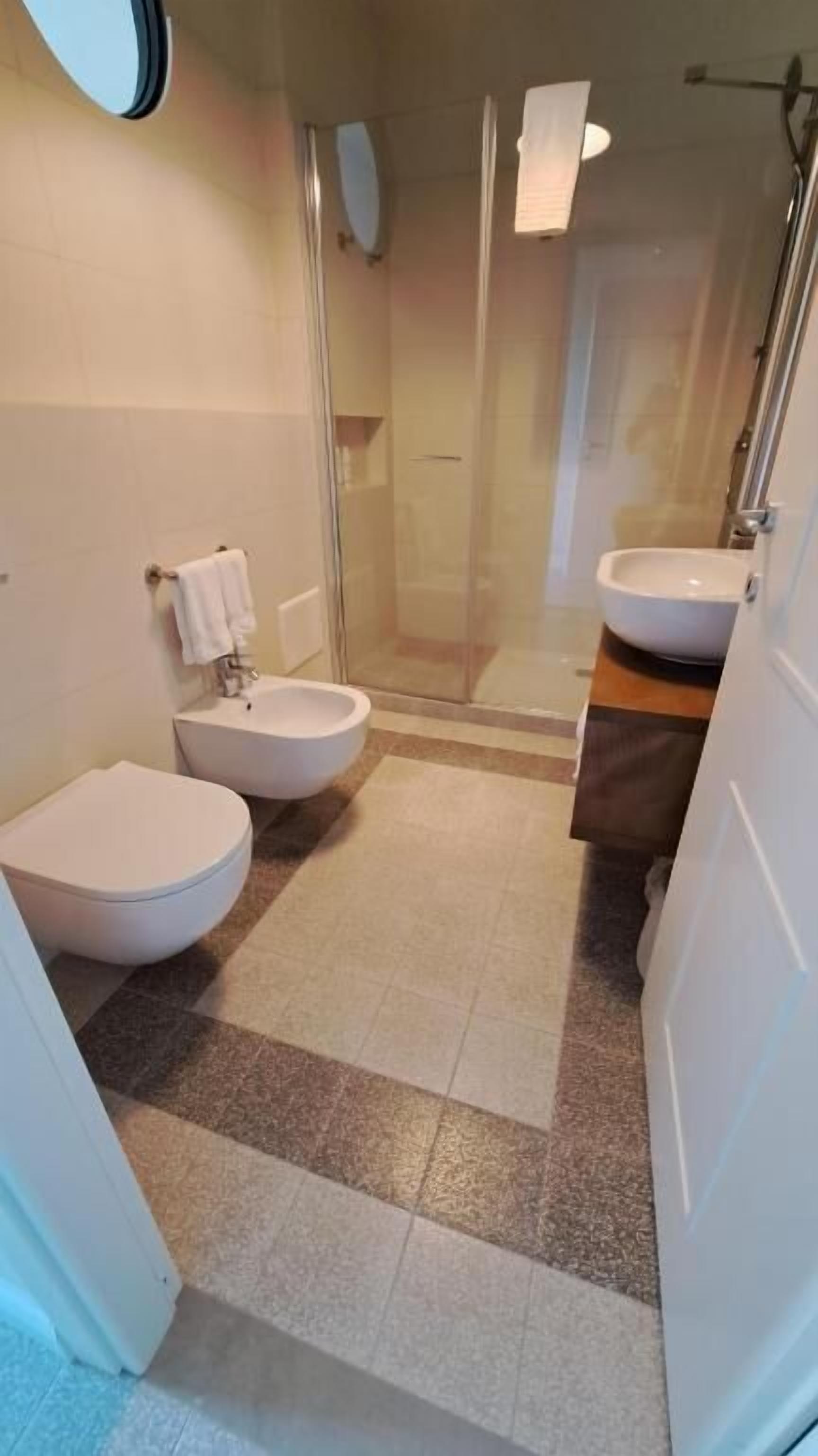 A bathroom with a toilet, bidet, and a glass-enclosed shower area.