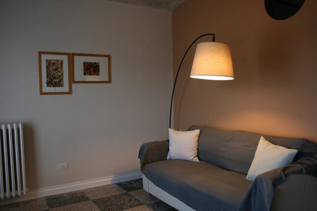 Ein Zimmer mit einer Couch, einer Lampe und zwei gerahmten Bildern an der Wand.