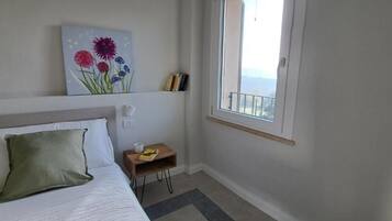 Ein Schlafzimmer mit Bett, Nachttisch, Fenster und einem Bild an der Wand.