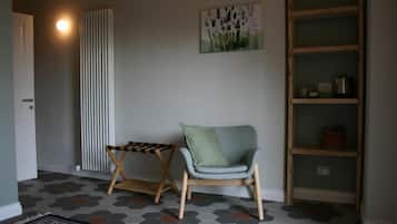 Ein Zimmer mit einem Sessel, einem kleinen Tisch, einer Heizung, einem Bücherregal und einem fußbodenhohen Hexagonmuster.