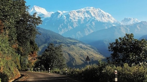 A road leading to a mountain range with a triangular warning sign.