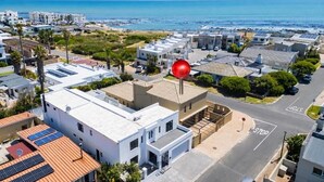 Un quartier résidentiel avec des maisons modernes, un panneau de signalisation indiquant un arrêt obligatoire et une vue sur l’océan.