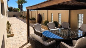 Une terrasse extérieure avec une table ronde et des chaises, entourée de cactus et de plantes en pot.