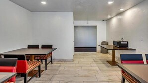 Un salón de conferencias con una larga mesa y sillas, una pequeña mesa con una computadora, y una puerta al fondo.